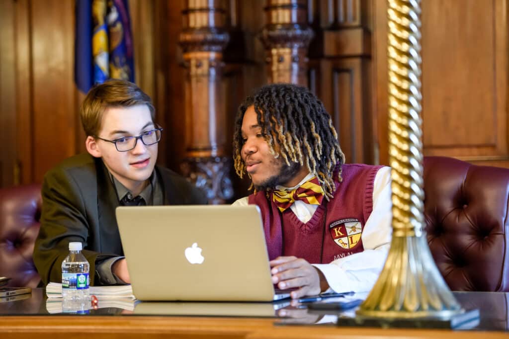 Image of two students in the courtroom looking at a computer